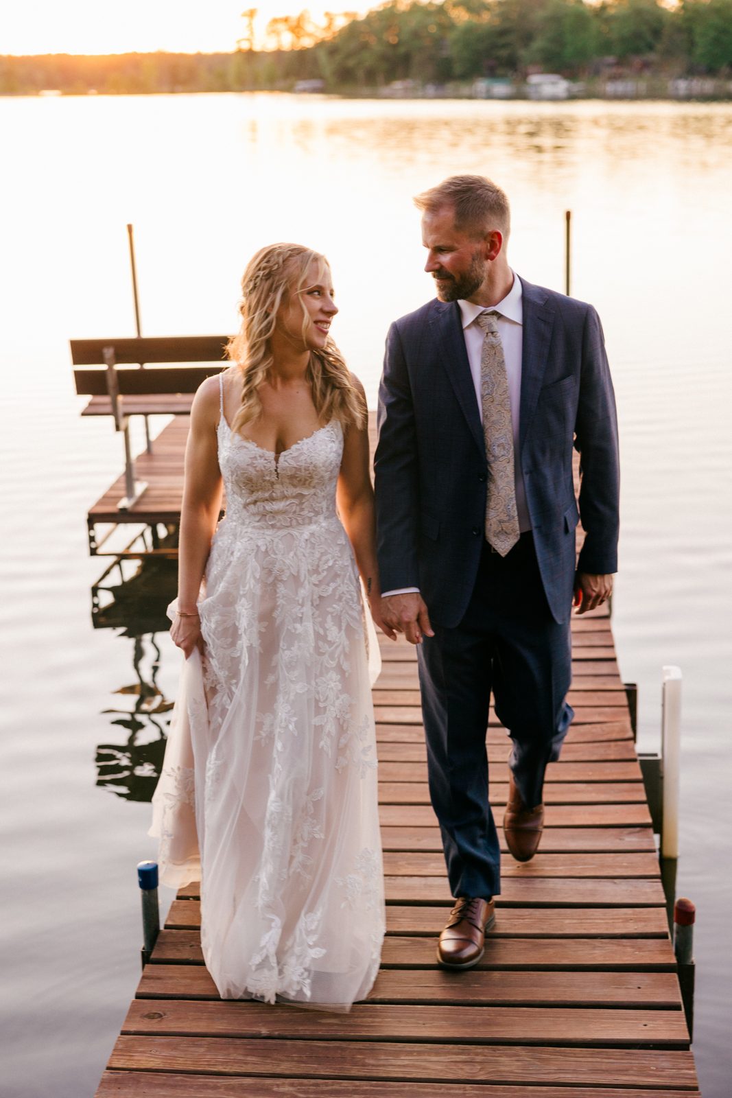 Couple walking down dock, lake glowing behind, eyes locked on each other. — Tim Larsen Photography, Brainerd Lakes MN