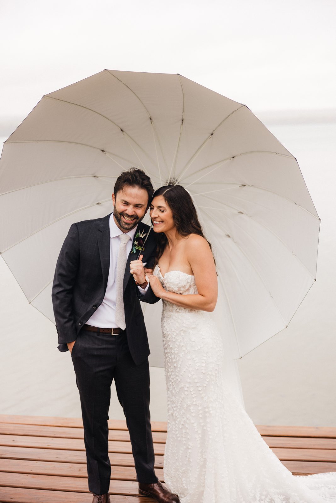 Large umbrella creates a domed canopy framing couple on dock against lake — Tim Larsen Photography, Brainerd Lakes MN