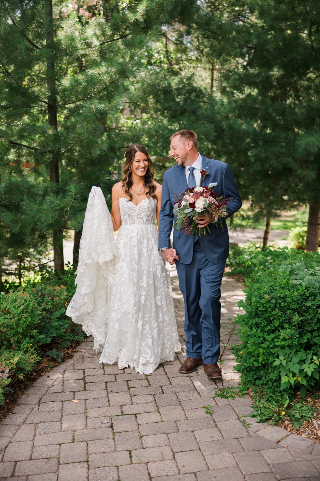 Bride and groom share a private laugh on the garden path between portraits at Manhattan Beach Lodge — Tim Larsen Photography, Brainerd Lakes MN