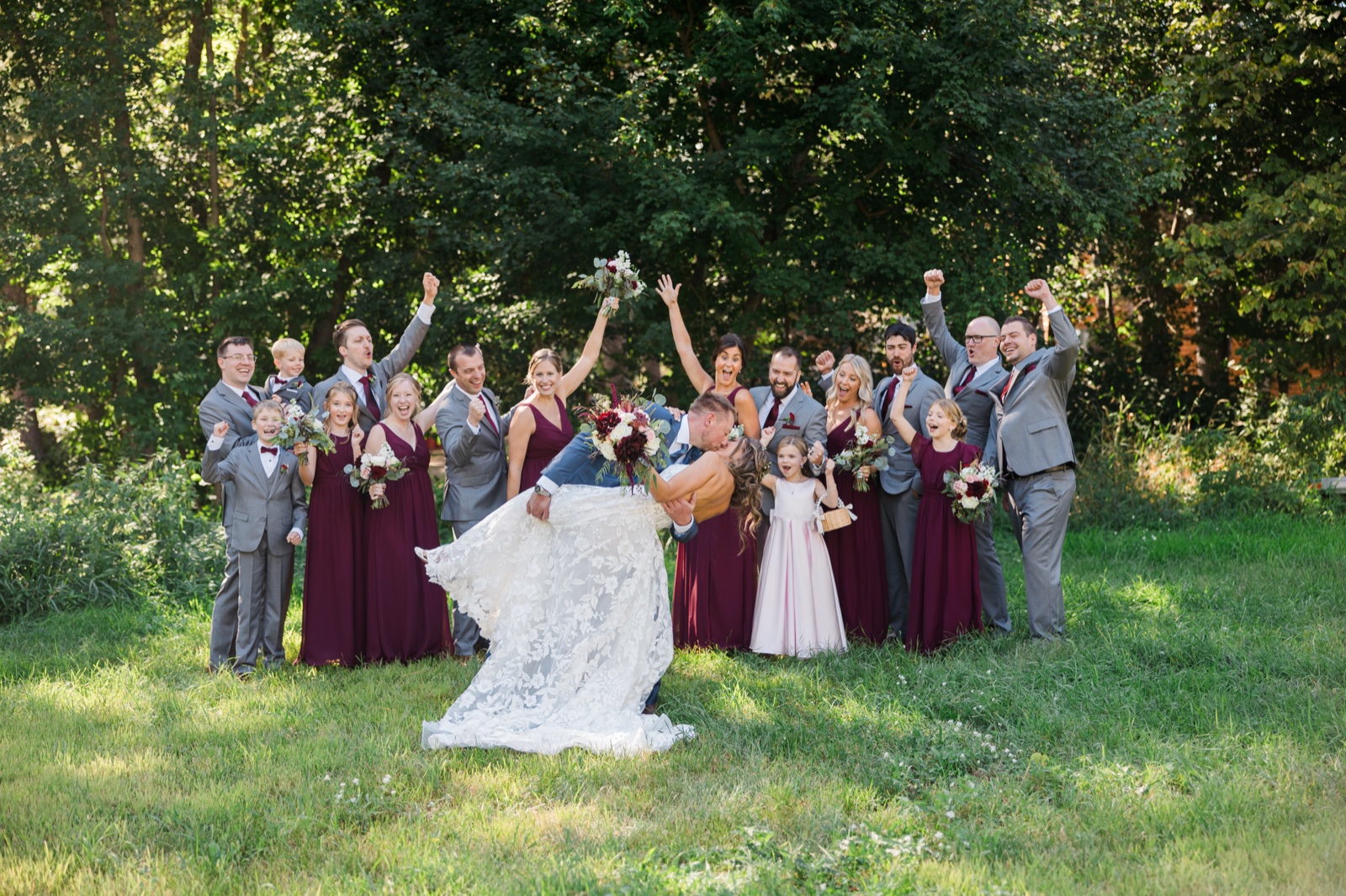 Groom dips the bride into a kiss as the bridal party cheers on the lawn at Manhattan Beach Lodge — Tim Larsen Photography, Brainerd Lakes MN