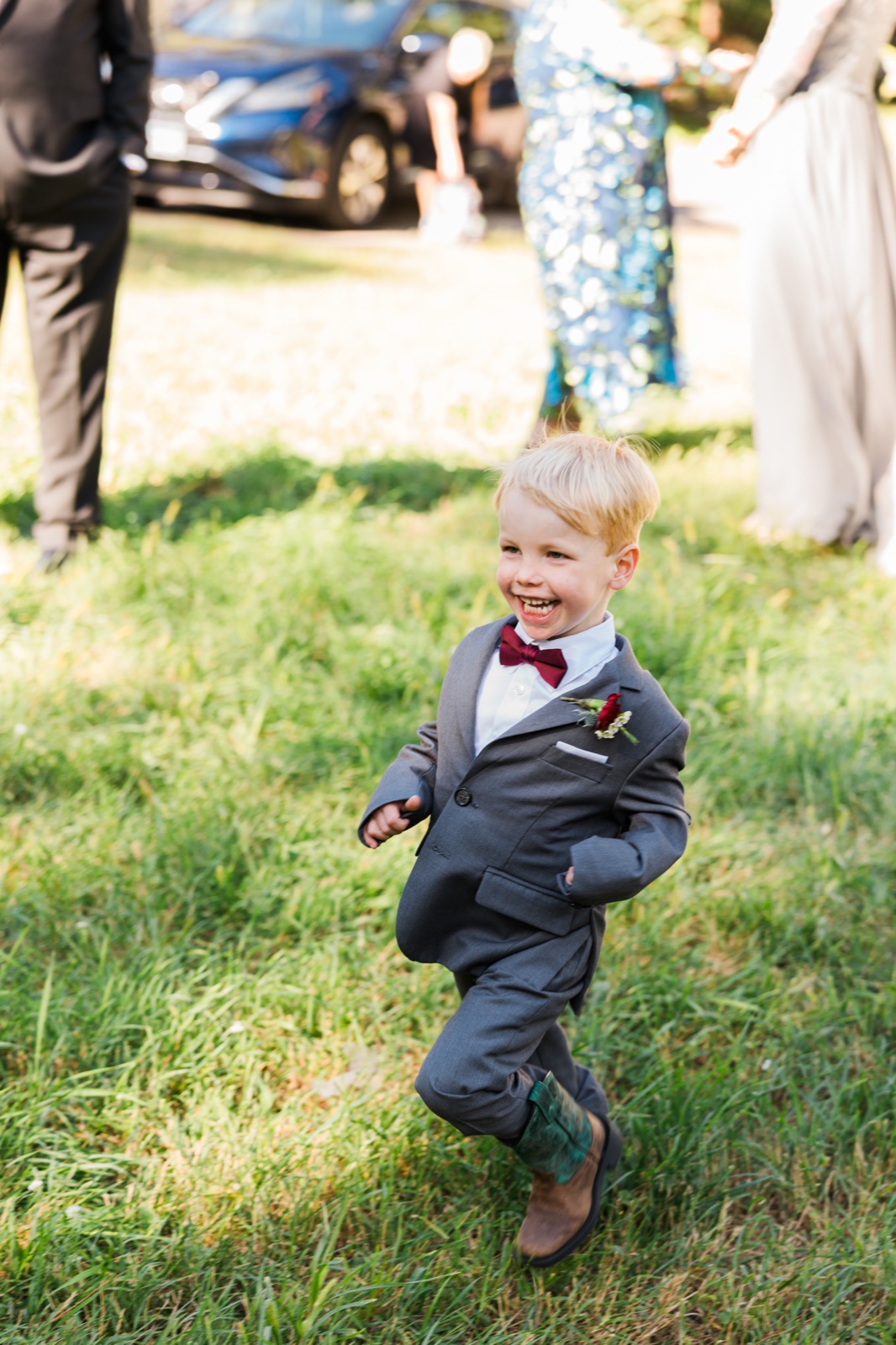 Ring bearer in cowboy boots runs across the lawn at Manhattan Beach Lodge — Tim Larsen Photography, Brainerd Lakes MN