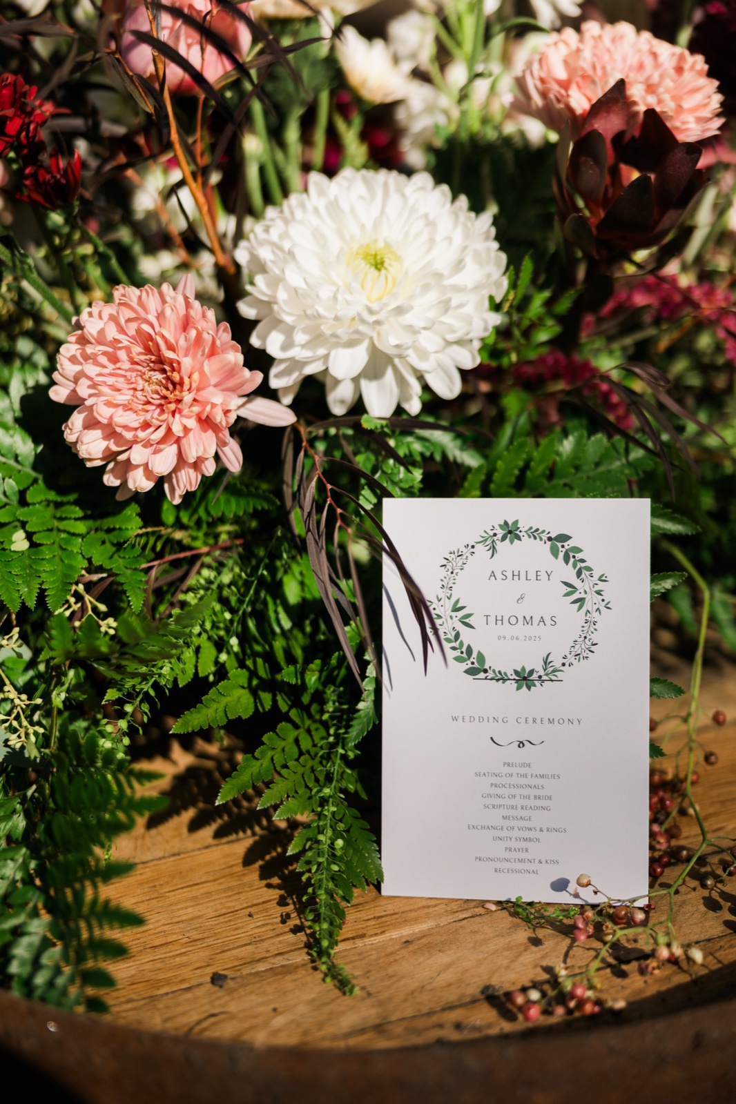 Ceremony program propped among protea, mums, and ferns on a wood barrel at Manhattan Beach Lodge — Tim Larsen Photography, Brainerd Lakes MN
