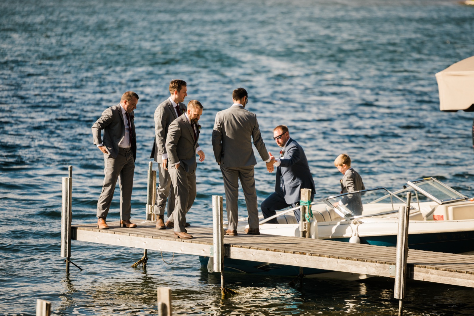 Groom and groomsmen walk the dock toward the waiting boat at Manhattan Beach Lodge — Tim Larsen Photography, Brainerd Lakes MN