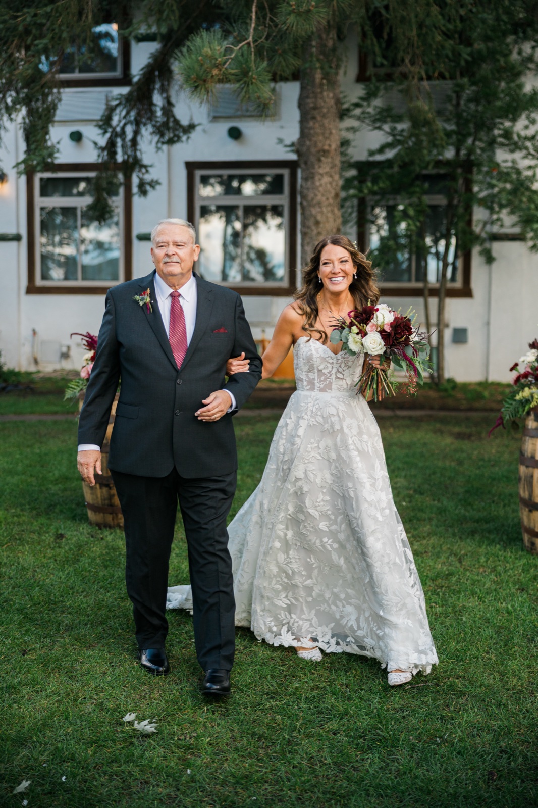 Bride walks arm-in-arm with her father down the grass aisle toward Manhattan Beach Lodge — Tim Larsen Photography, Brainerd Lakes MN
