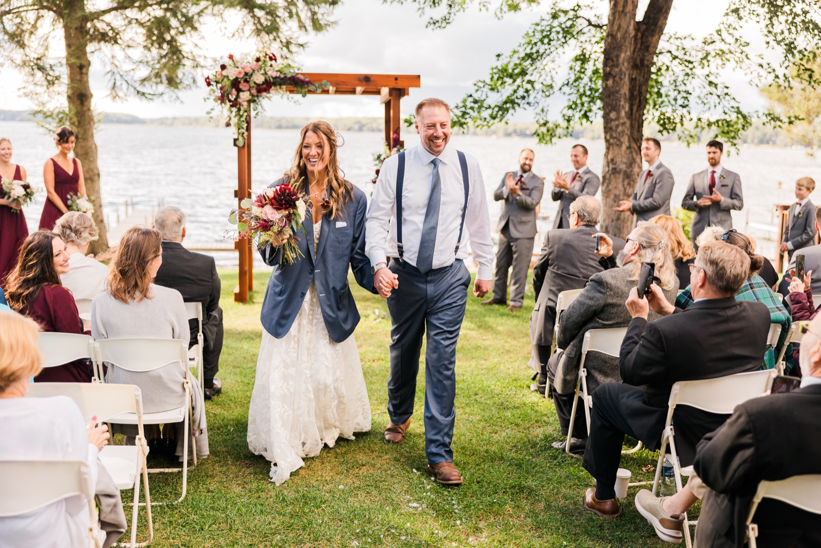 Bride and groom walk the recessional down the grass aisle at the lakeside ceremony on Big Trout Lake — Tim Larsen Photography, Brainerd Lakes MN