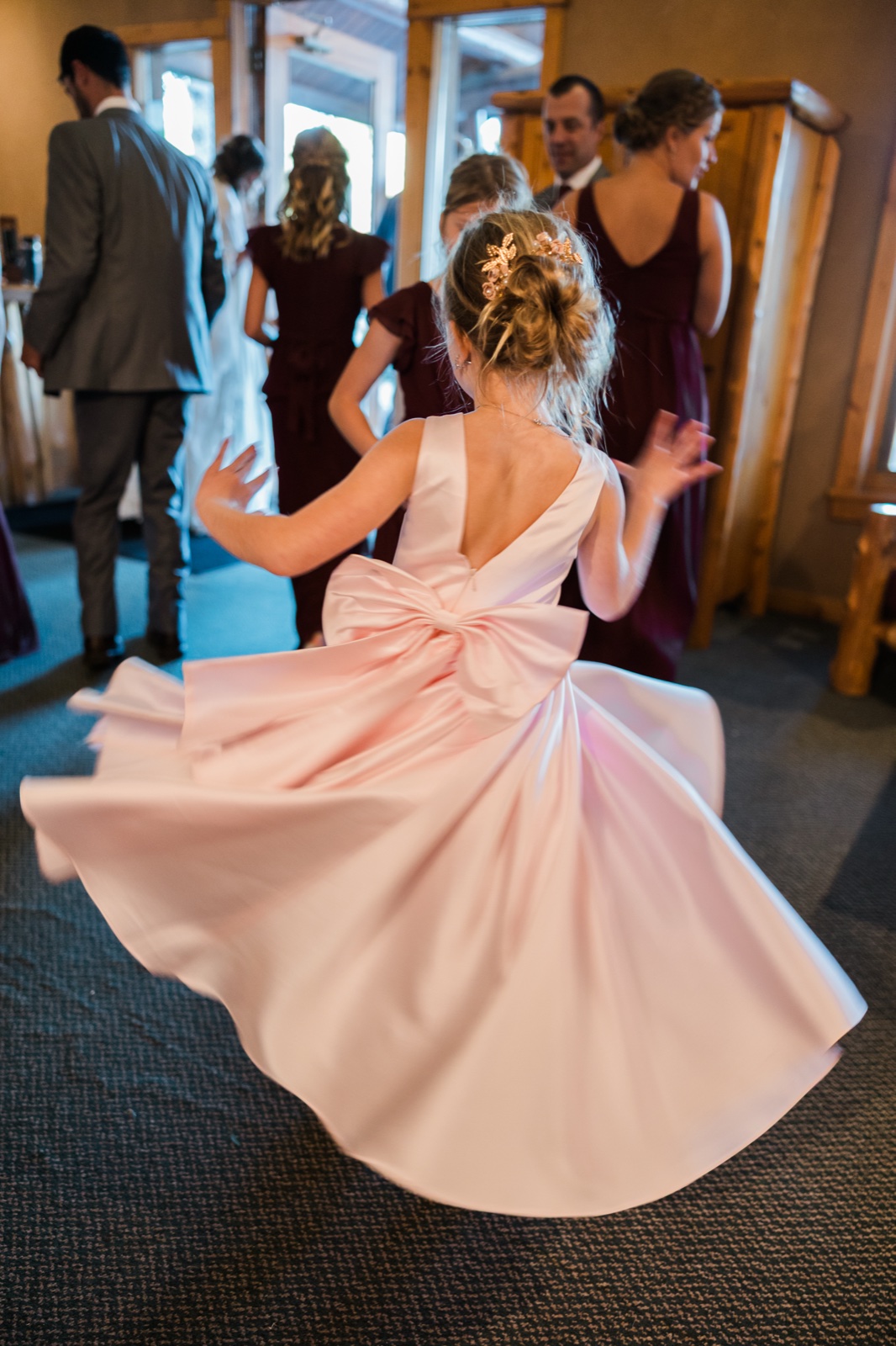 Flower girl twirls in a blush gown inside the wood-paneled lodge at Manhattan Beach Lodge — Tim Larsen Photography, Brainerd Lakes MN