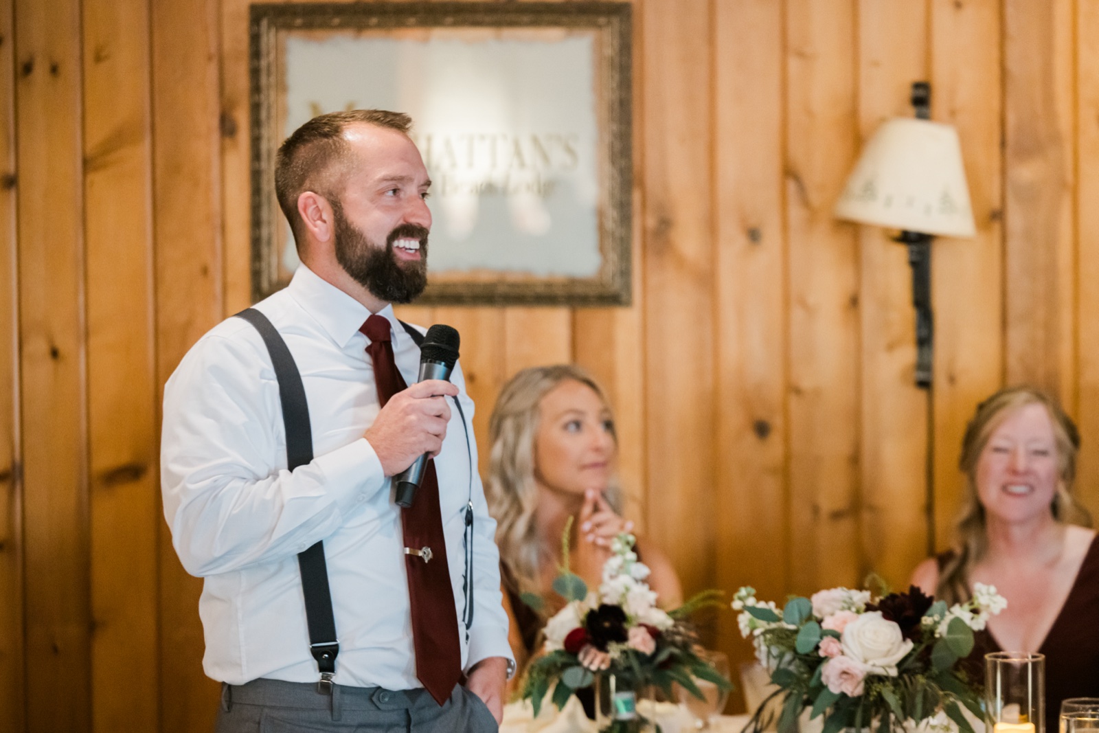 Groom delivers a toast beside the framed Manhattan Beach Lodge sign on knotty pine walls — Tim Larsen Photography, Brainerd Lakes MN