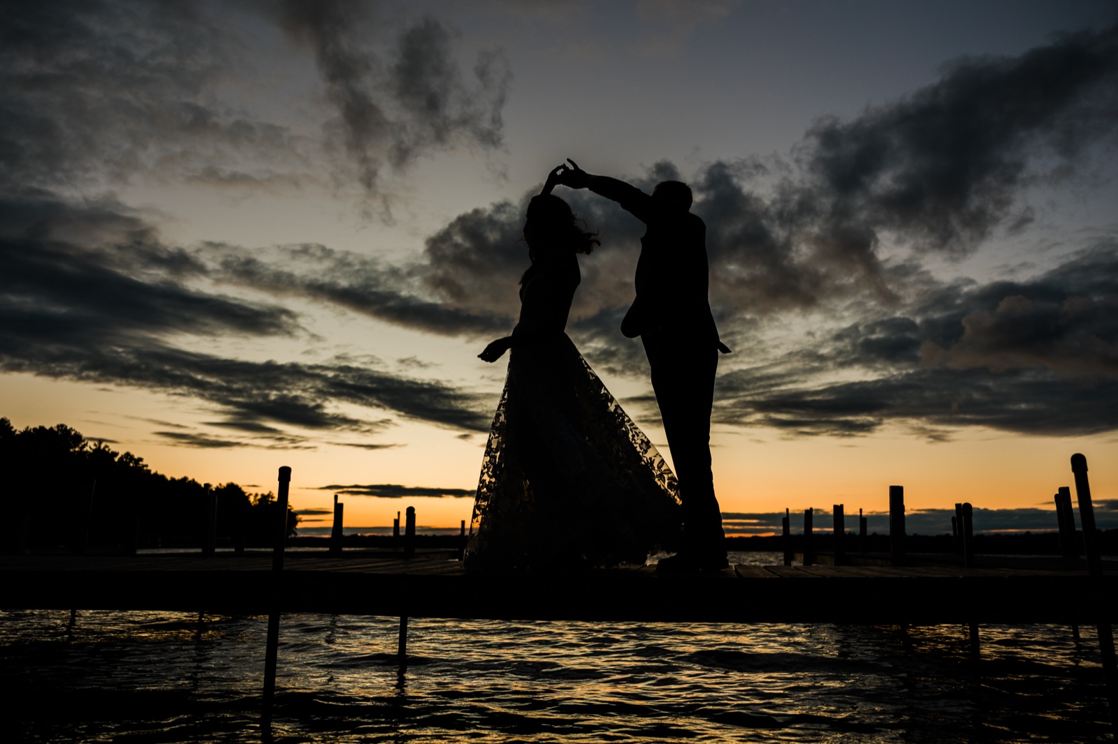 Silhouette of groom twirling bride on the Manhattan Beach Lodge dock at dusk over Big Trout Lake — Tim Larsen Photography, Brainerd Lakes MN