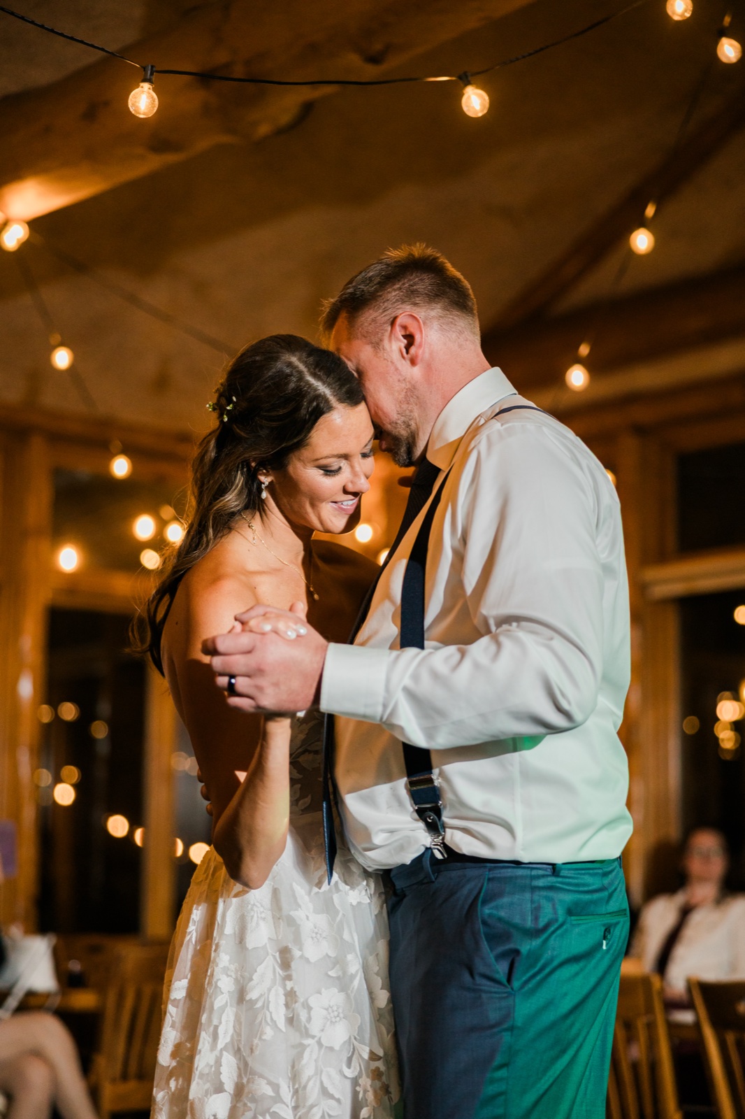 First dance beneath string lights in the wood-beamed reception hall at Manhattan Beach Lodge — Tim Larsen Photography, Brainerd Lakes MN