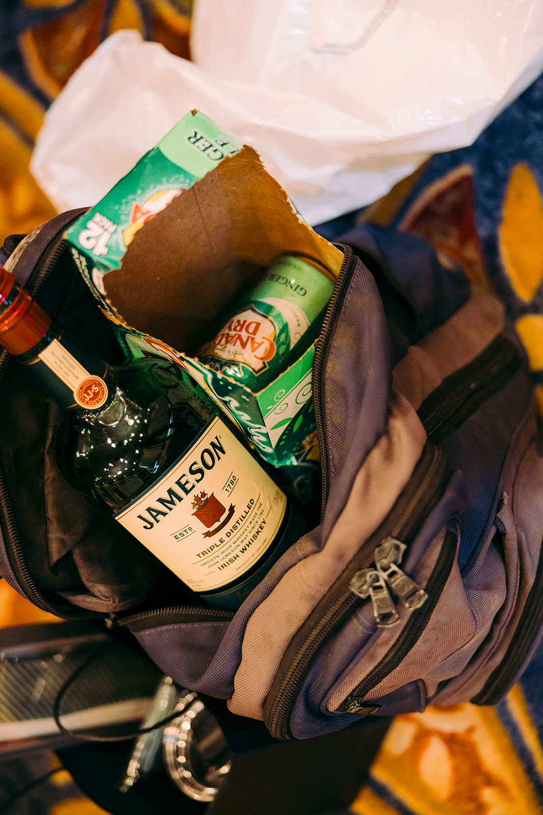 Groomsmen's getting-ready detail — Jameson whiskey and Angry Orchard in an open backpack — Tim Larsen Photography, Brainerd Lakes MN