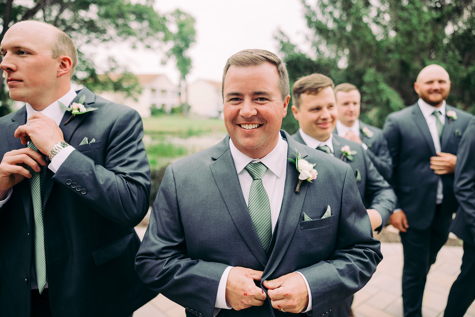 Groomsmen candid before the ceremony — groom smiling as he buttons his jacket — Tim Larsen Photography, Brainerd Lakes MN