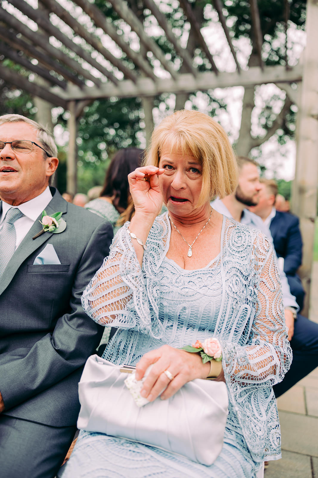 Mother of the bride emotional during the outdoor ceremony, clutching a tissue in a lace dress — Tim Larsen Photography, Brainerd Lakes MN