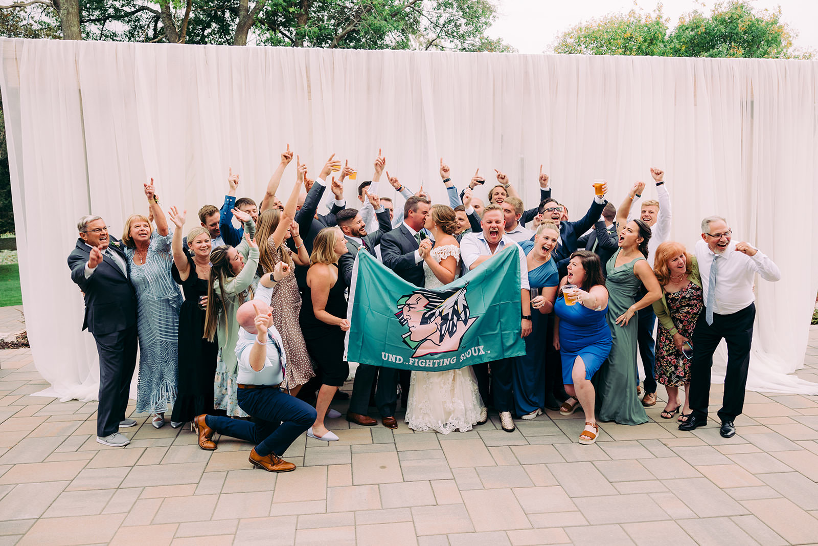 Family and friends celebrating with a UND Fighting Sioux flag at the Madden's on Gull Lake reception — Tim Larsen Photography, Brainerd Lakes MN