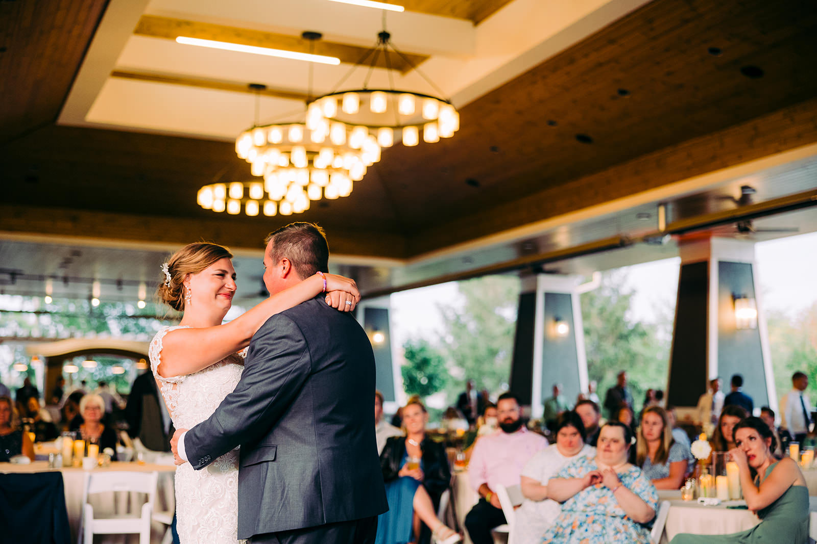 First dance in the reception space — coffered wood ceiling and a large globe pendant chandelier overhead — Tim Larsen Photography, Brainerd Lakes MN