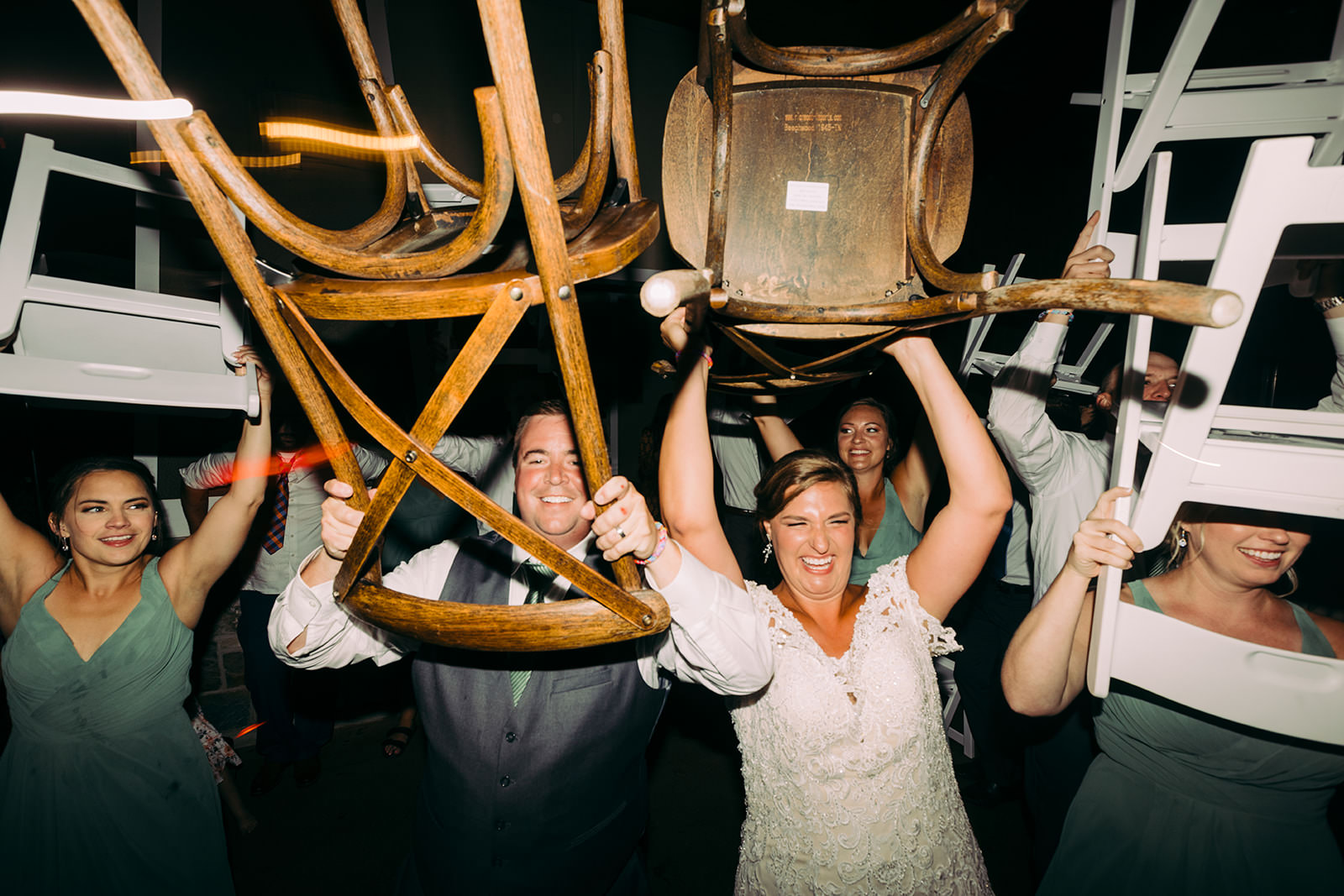 Reception moment — guests lifting chairs in the air during a celebratory lift, bride laughing mid-crowd — Tim Larsen Photography, Brainerd Lakes MN