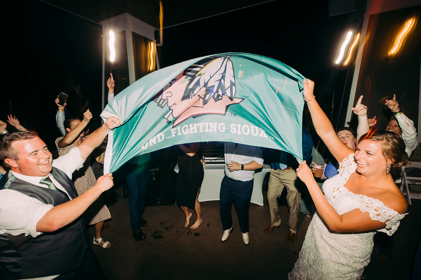 Guests holding a UND Fighting Sioux flag mid-dance on the reception floor — Tim Larsen Photography, Brainerd Lakes MN