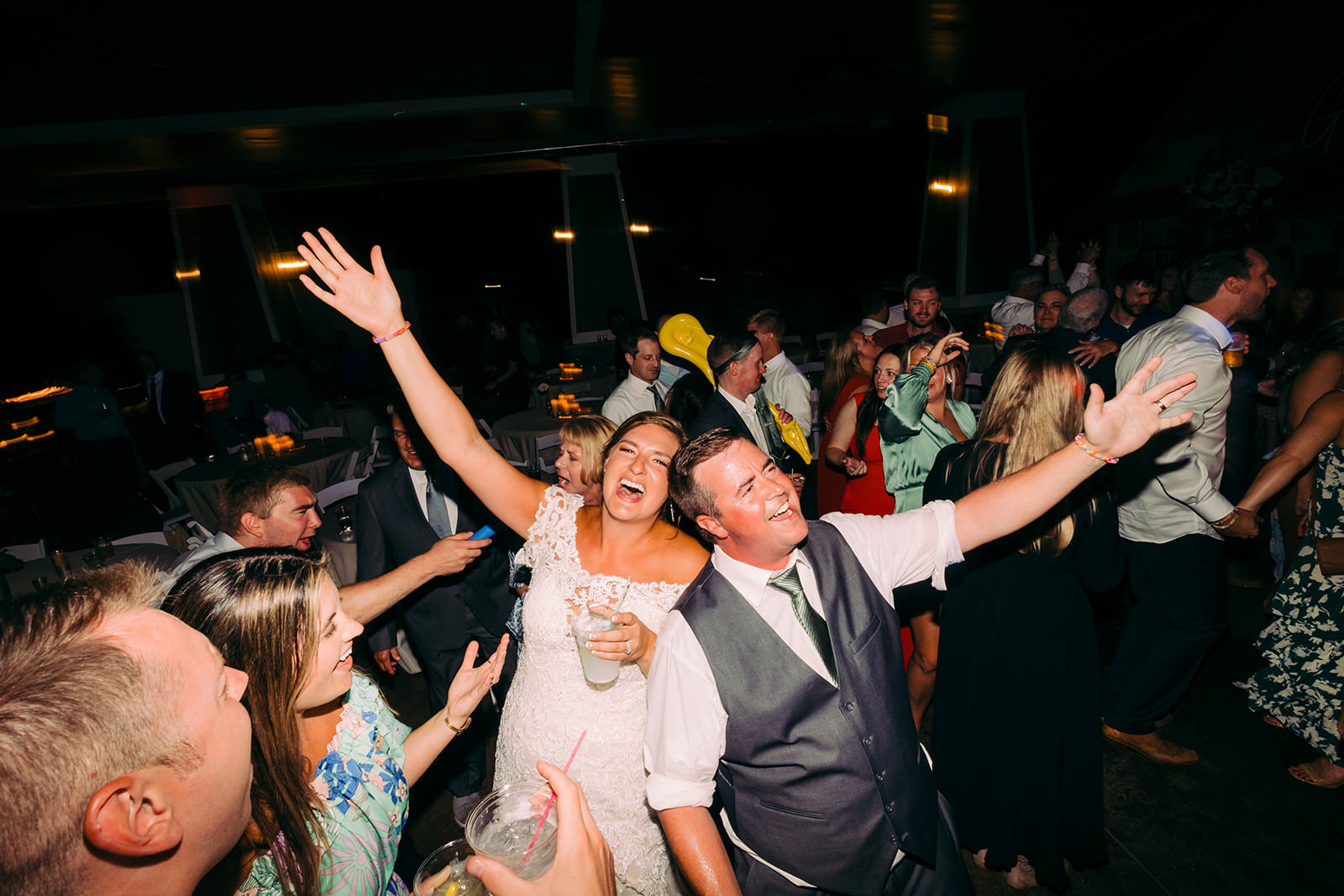 Couple mid-cheer on the dance floor, surrounded by friends — Tim Larsen Photography, Brainerd Lakes MN