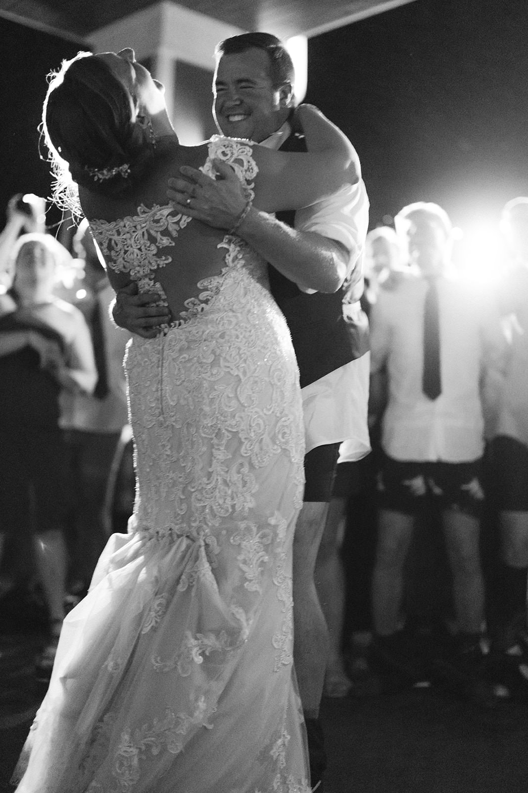 Black and white final dance — couple holding each other, the dance floor lights fading behind — Tim Larsen Photography, Brainerd Lakes MN