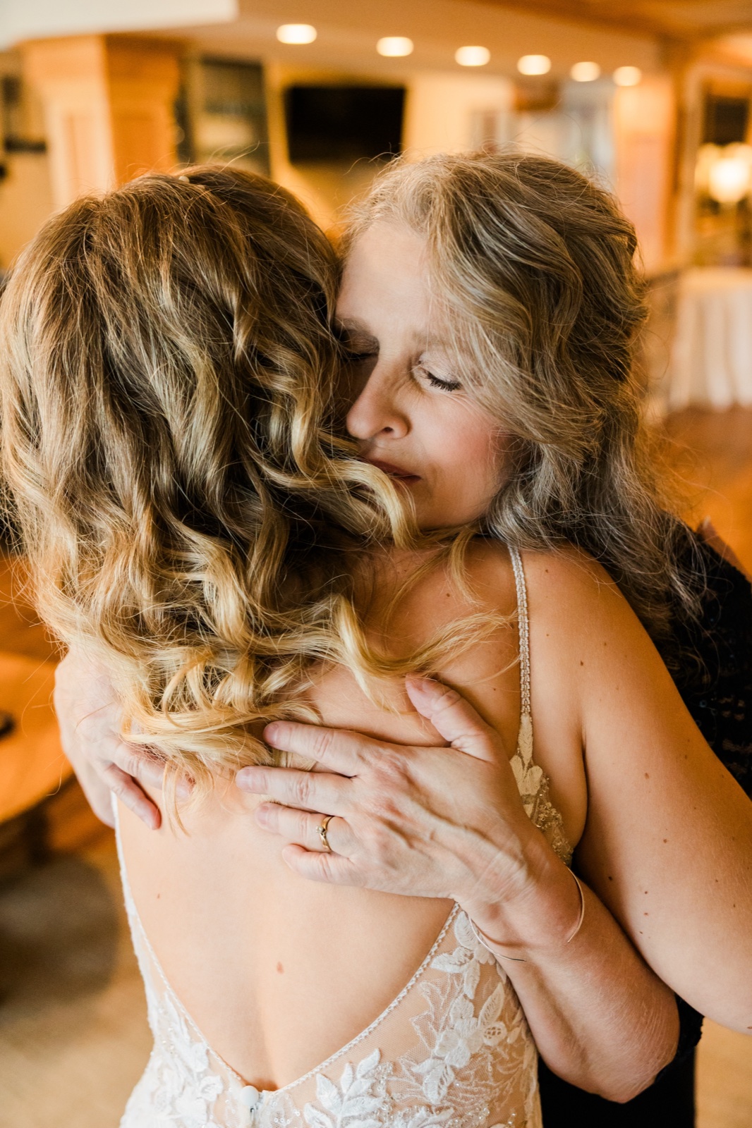 Mother embracing the bride from behind in a quiet pre-ceremony moment at Madden's