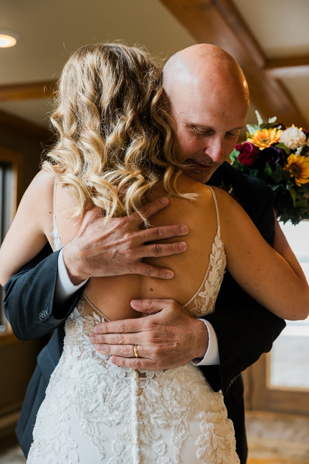 Groom holding the bride close after their first look, wedding band against the lace of her dress