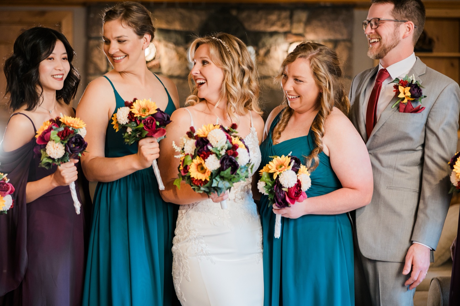 Bride, bridal party and groom sharing a laugh in front of the stone fireplace at Madden's on Gull Lake