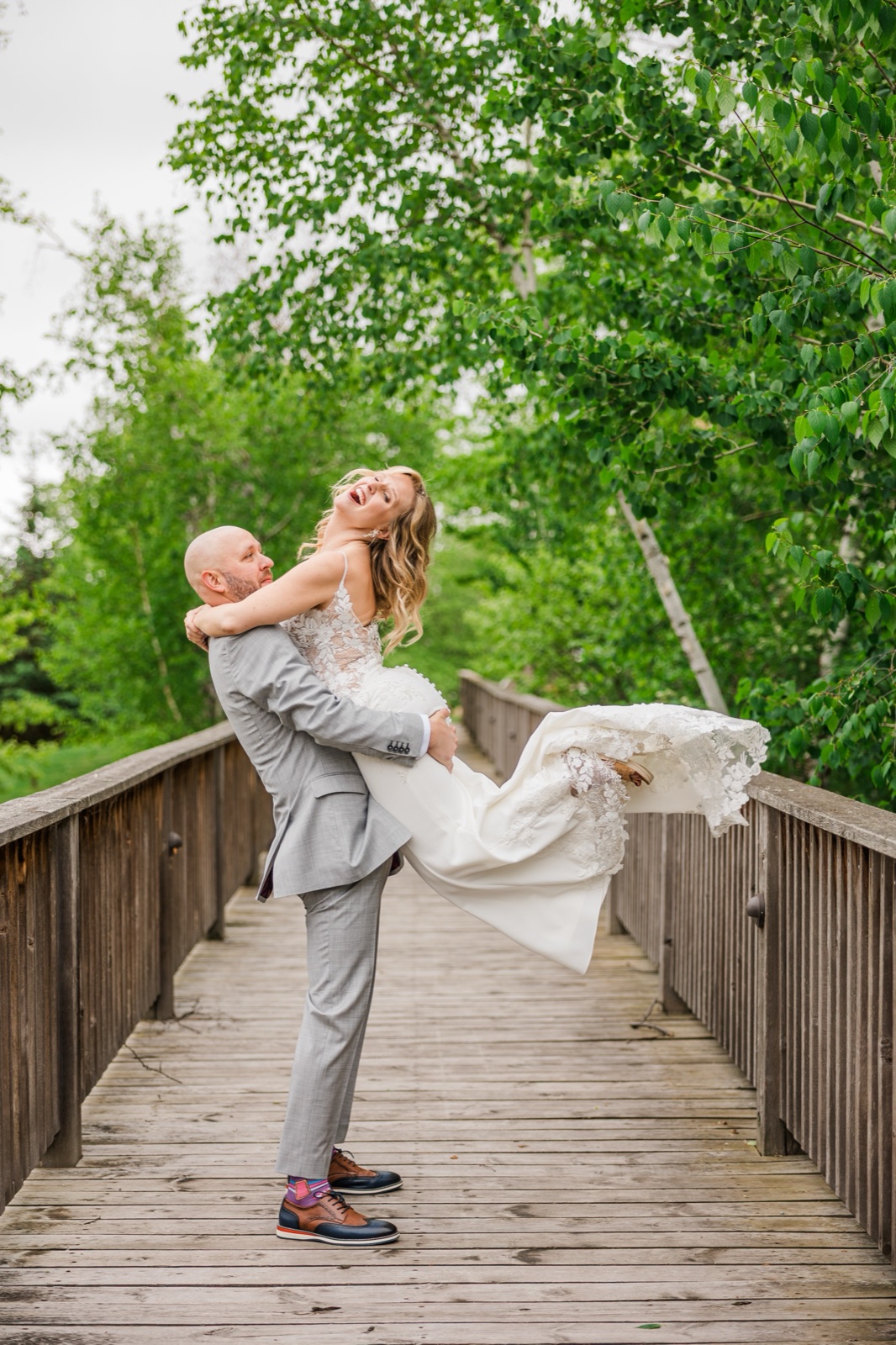 Groom lifting the laughing bride off her feet on a birch-lined footbridge at Madden's on Gull Lake — Tim Larsen Photography, Brainerd Lakes MN