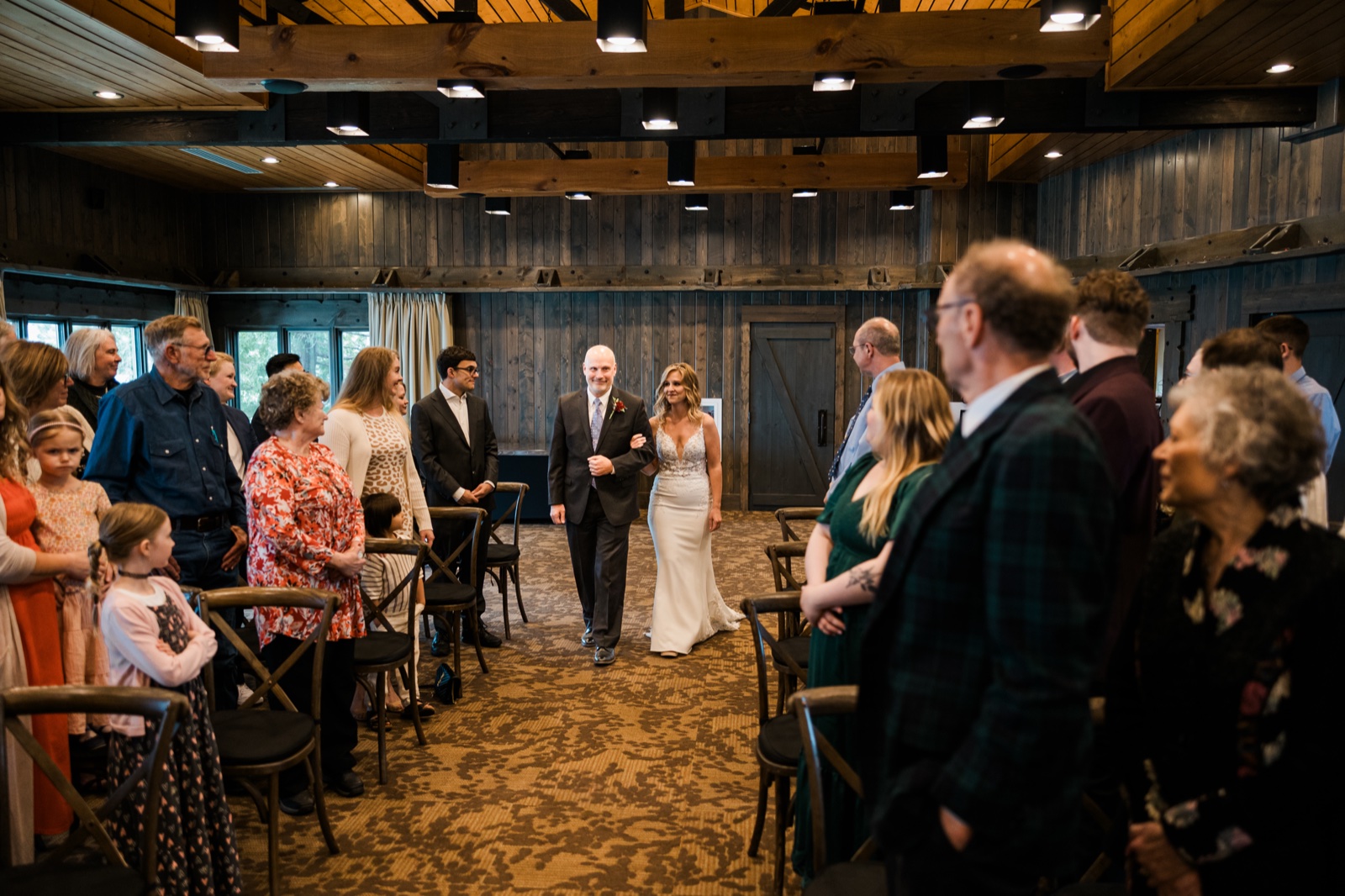 Bride and groom walking in together down the aisle beneath heavy timber beams at Madden's on Gull Lake