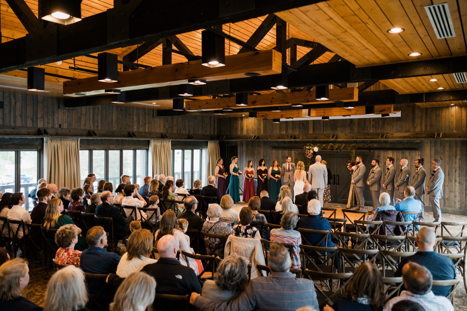 Wide view of the wedding ceremony under the timber beams of the Madden's pavilion