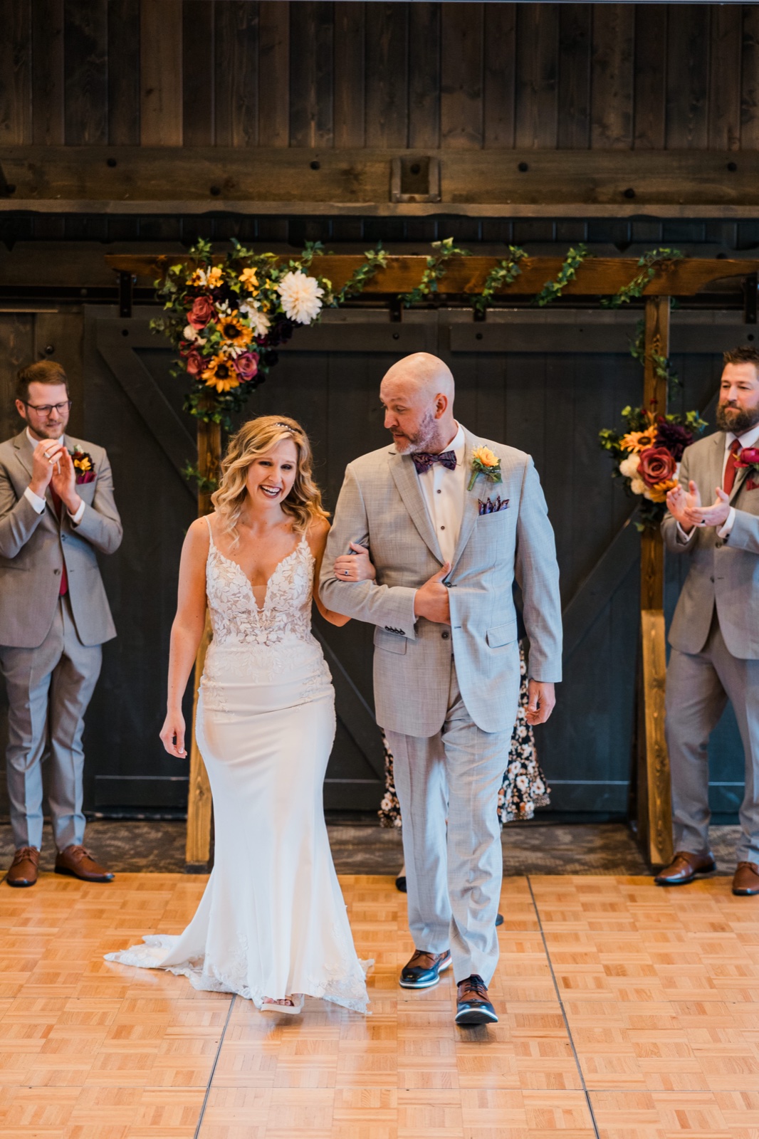 Bride laughing during the recessional under floral-draped barn doors at Madden's — Tim Larsen Photography, Brainerd Lakes MN