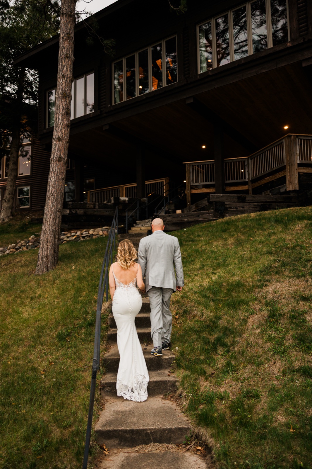 Bride and groom climbing stone steps back toward the lodge at Madden's between portraits and reception