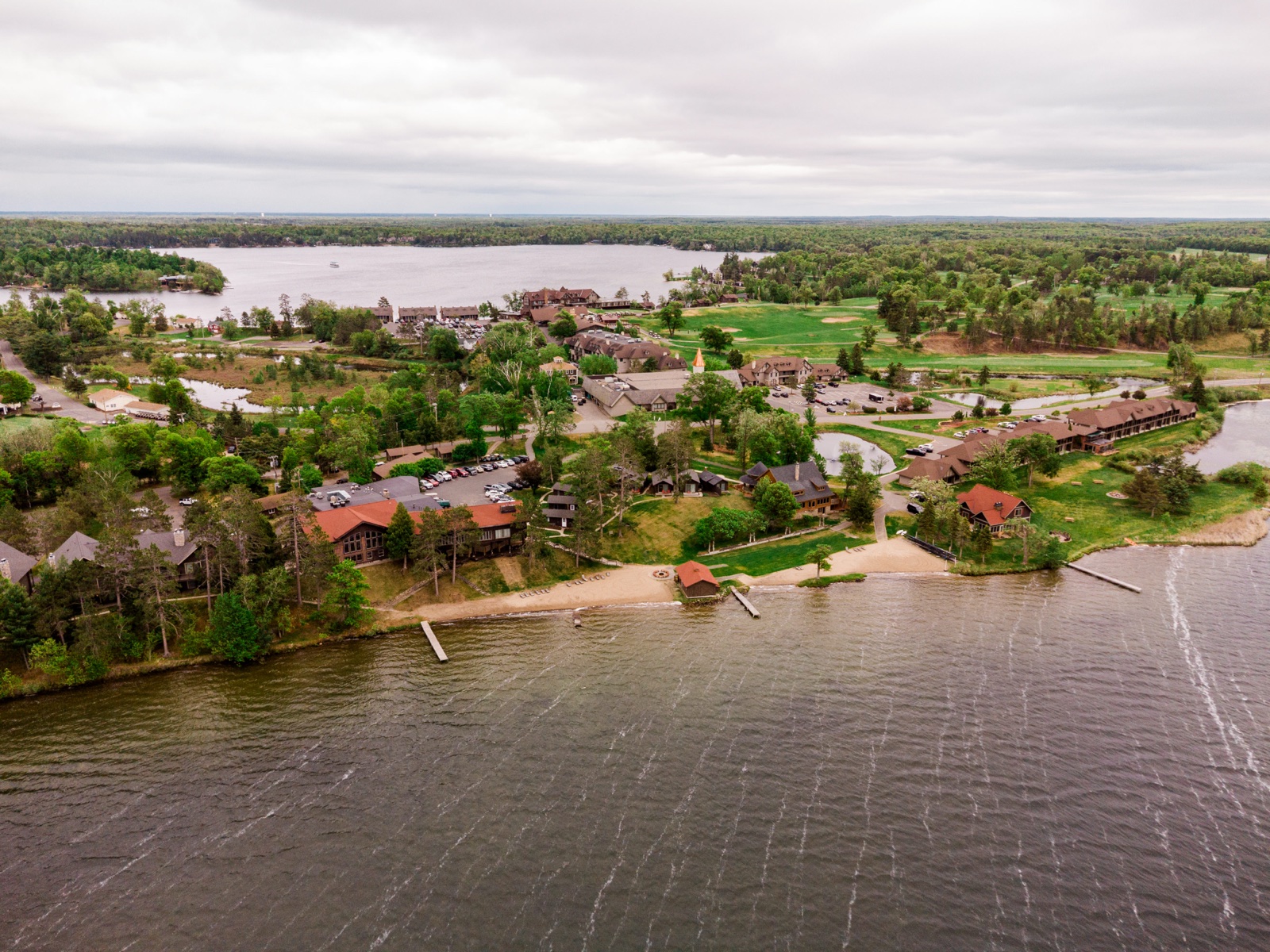 Aerial view of Madden's on Gull Lake resort, main lodge and cabins along the Gull Lake shoreline under spring skies — Tim Larsen Photography, Brainerd Lakes MN