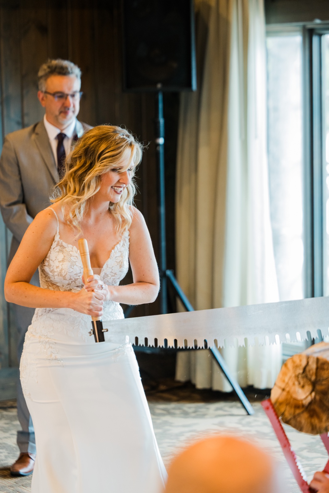 Bride gripping a two-person log saw for a Northwoods reception tradition at Madden's on Gull Lake
