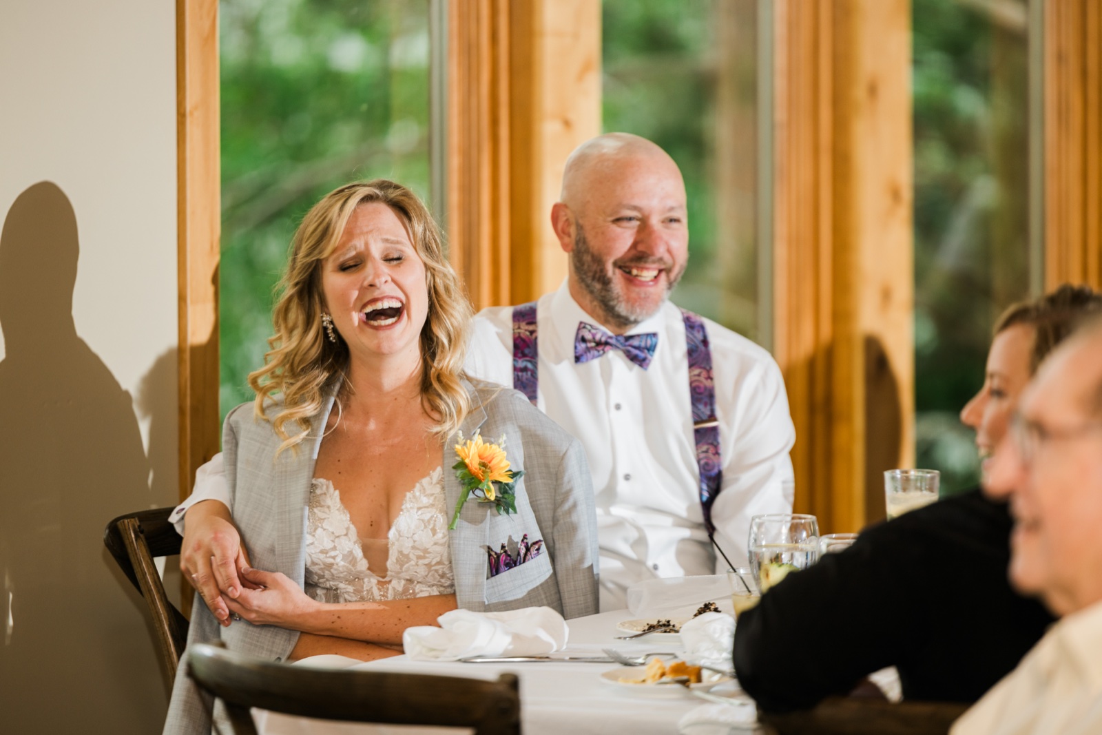 Bride laughing with her head tipped back during toasts at the head table
