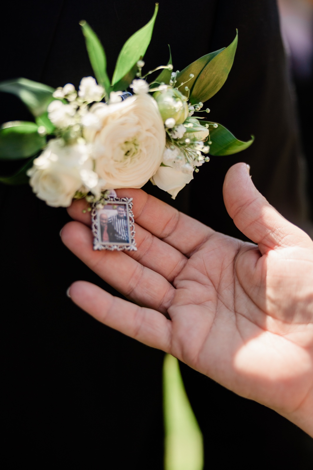 The bride's hand holds a white bouquet with a framed memorial photo charm tucked among the blooms — Tim Larsen Photography, Brainerd Lakes MN