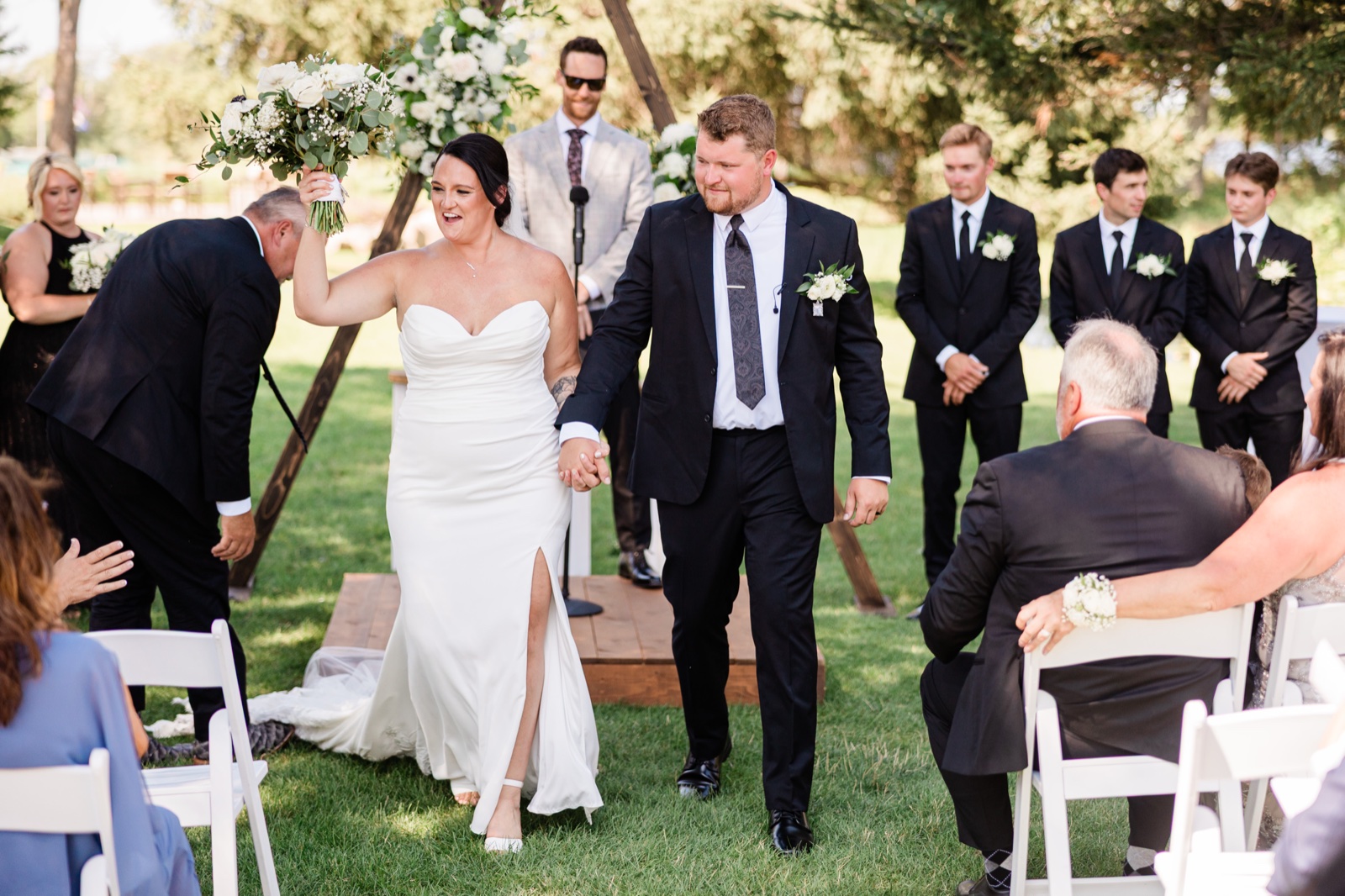Recessional — the bride raises her bouquet triumphantly as she and the groom walk hand-in-hand back down the aisle at Madden's — Tim Larsen Photography, Brainerd Lakes MN