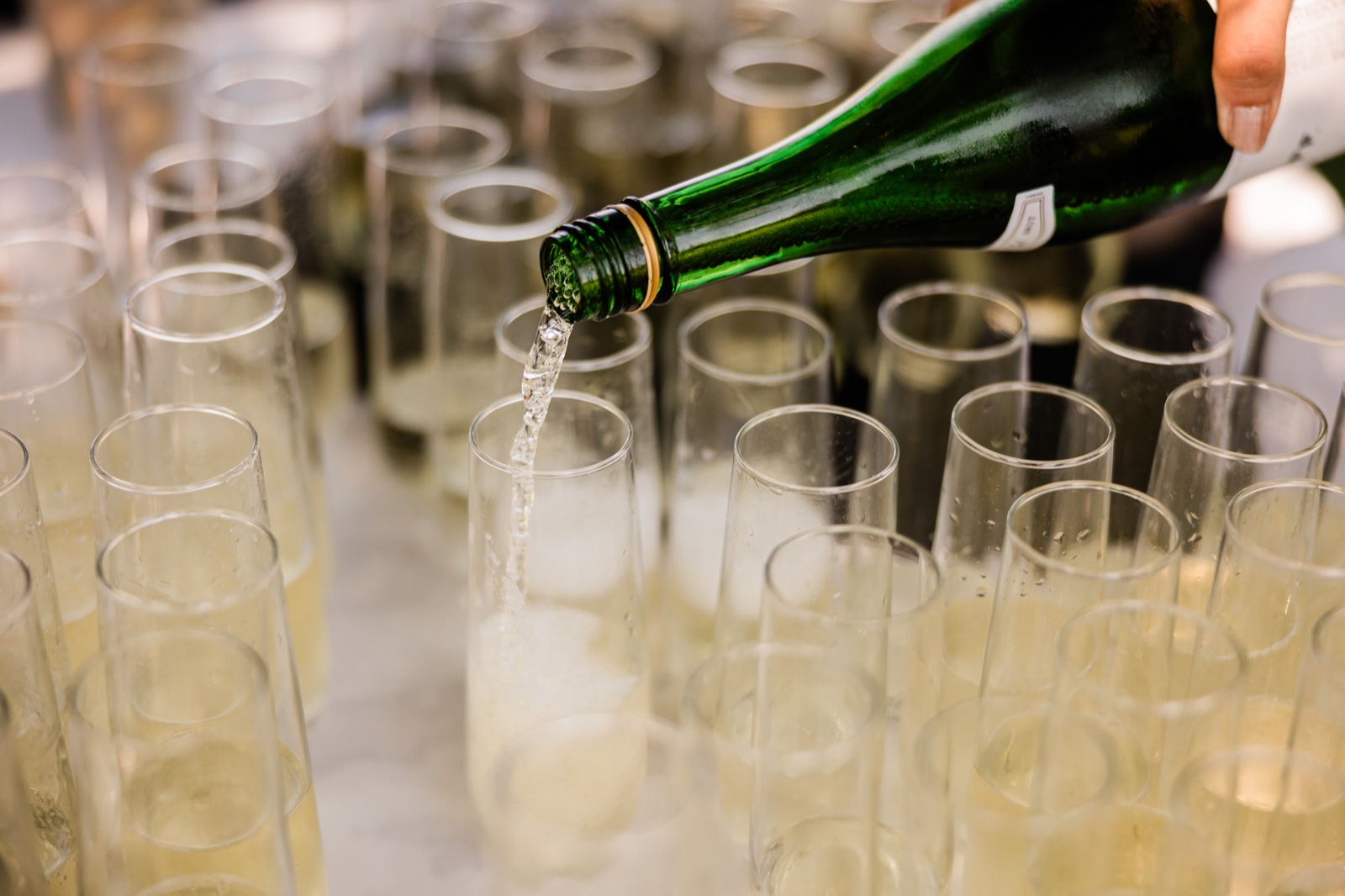 A server pours champagne from a green bottle into rows of stemless flutes ahead of cocktail hour at Madden's on Gull Lake — Tim Larsen Photography, Brainerd Lakes MN