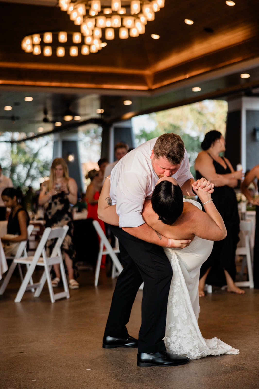 The groom dips the bride into a kiss on the first-dance floor beneath an illuminated chandelier ceiling at Madden's Pavilion — Tim Larsen Photography, Brainerd Lakes MN