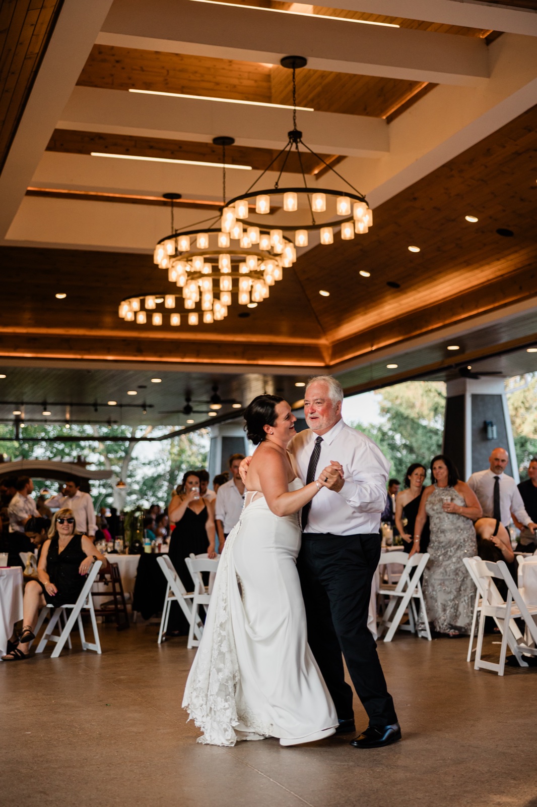Father-daughter dance on the Madden's Pavilion floor beneath the venue's tiered chandeliers, guests watching from surrounding tables — Tim Larsen Photography, Brainerd Lakes MN