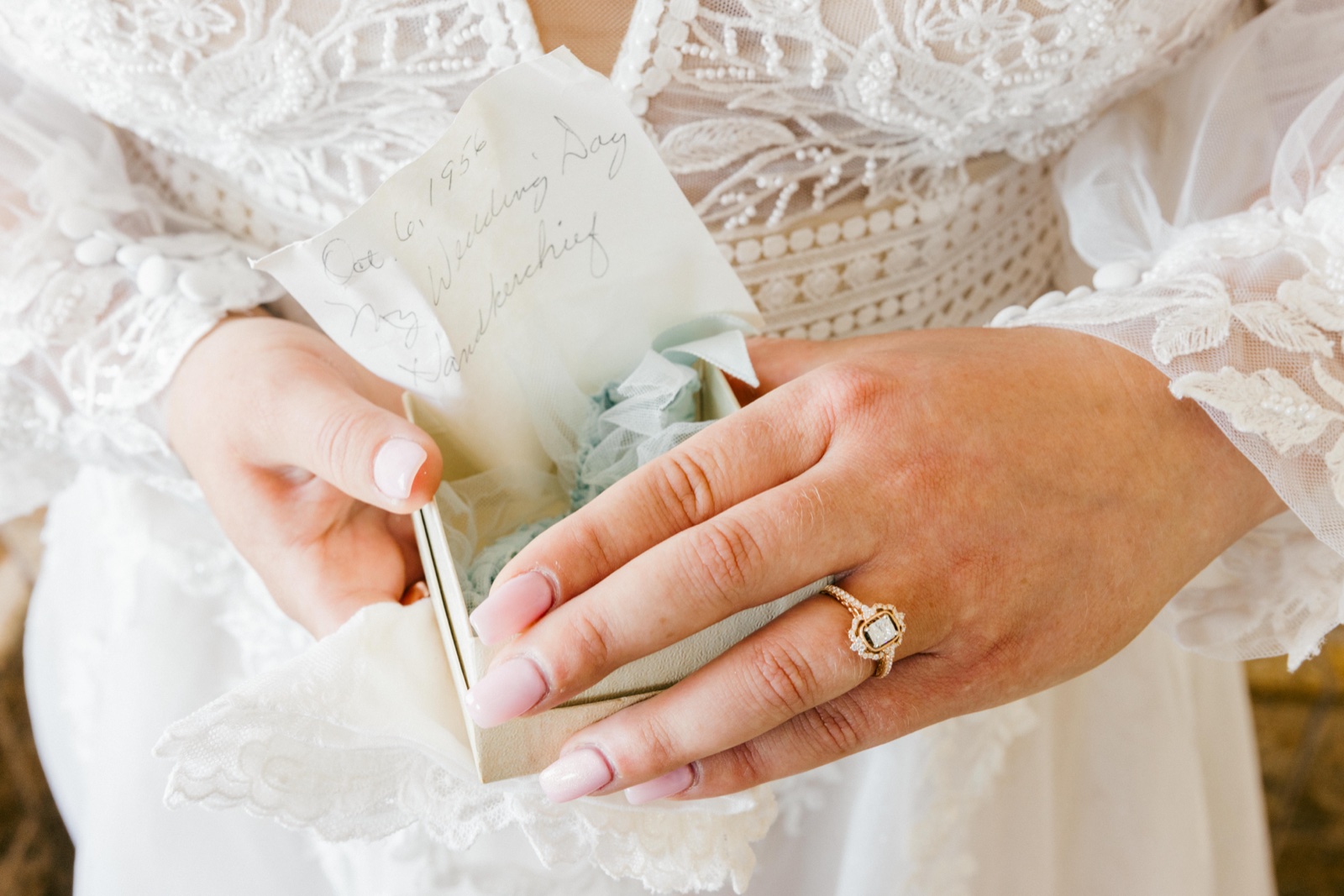The bride's hands hold an open ring box with a pale blue heirloom handkerchief and a handwritten note dated October 6, 1956 — Tim Larsen Photography, Brainerd Lakes MN