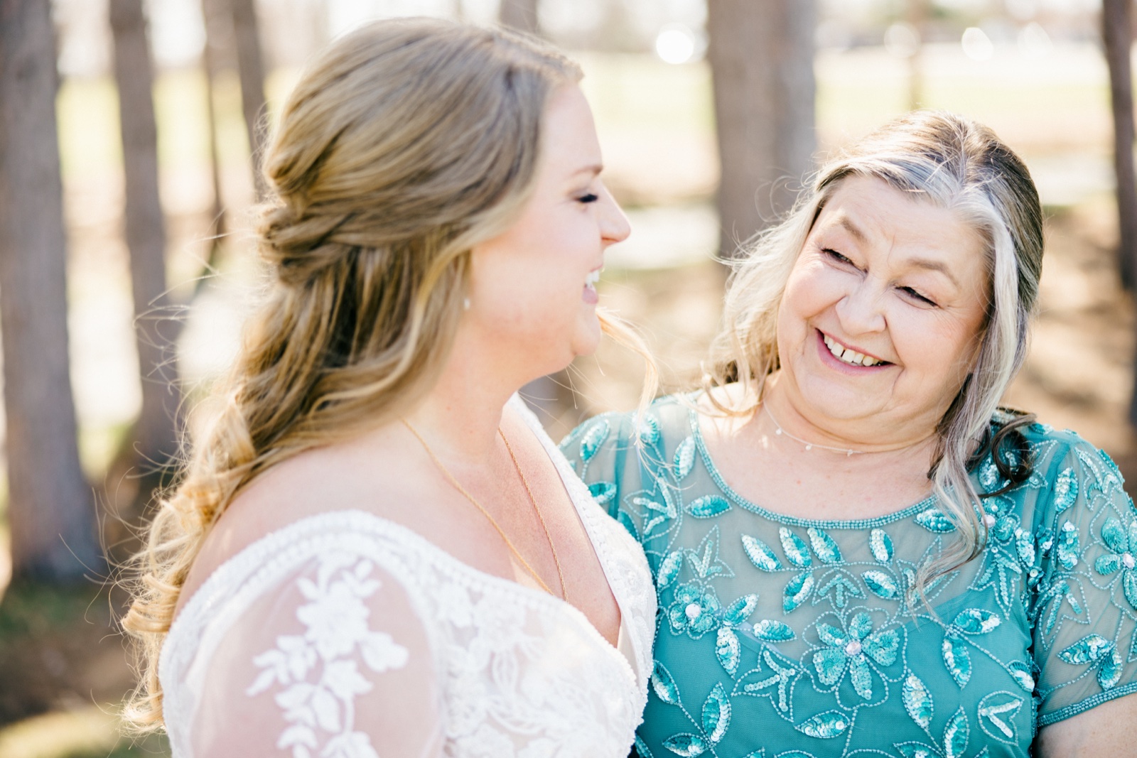 The bride and her mother share an unguarded laugh together among backlit pines at Cragun's Resort — Tim Larsen Photography, Brainerd Lakes MN