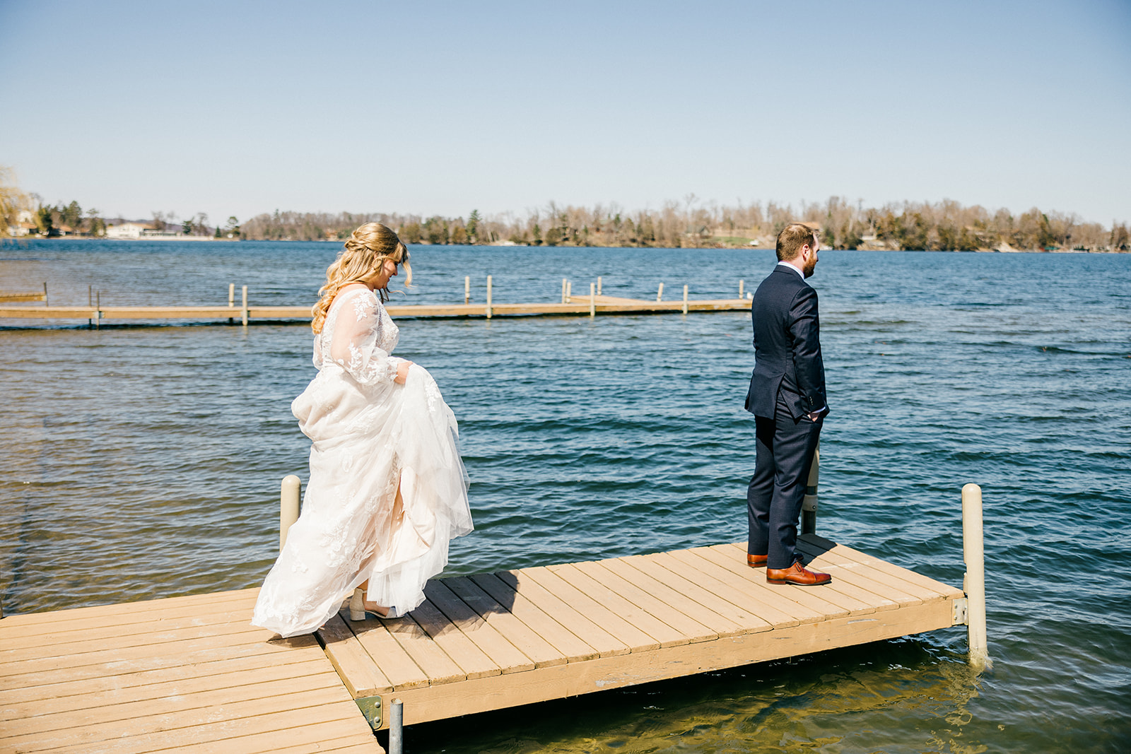 First look on the Gull Lake dock at Cragun's Legacy Golf Course — bride walking toward groom who faces the water — Tim Larsen Photography, Brainerd Lakes MN
