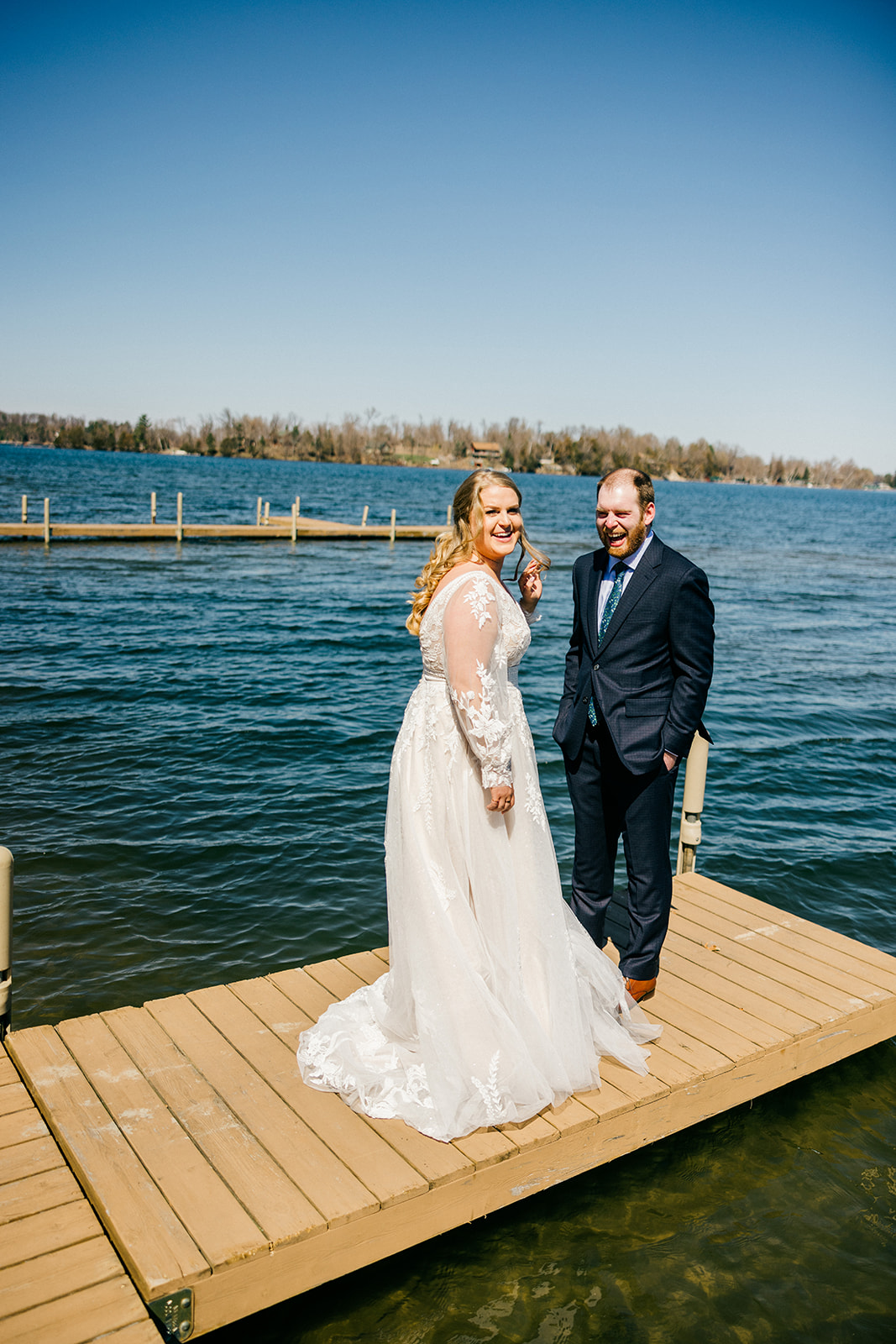 Bride and groom on the Gull Lake dock after the first look, clear blue spring sky behind them — Tim Larsen Photography, Brainerd Lakes MN