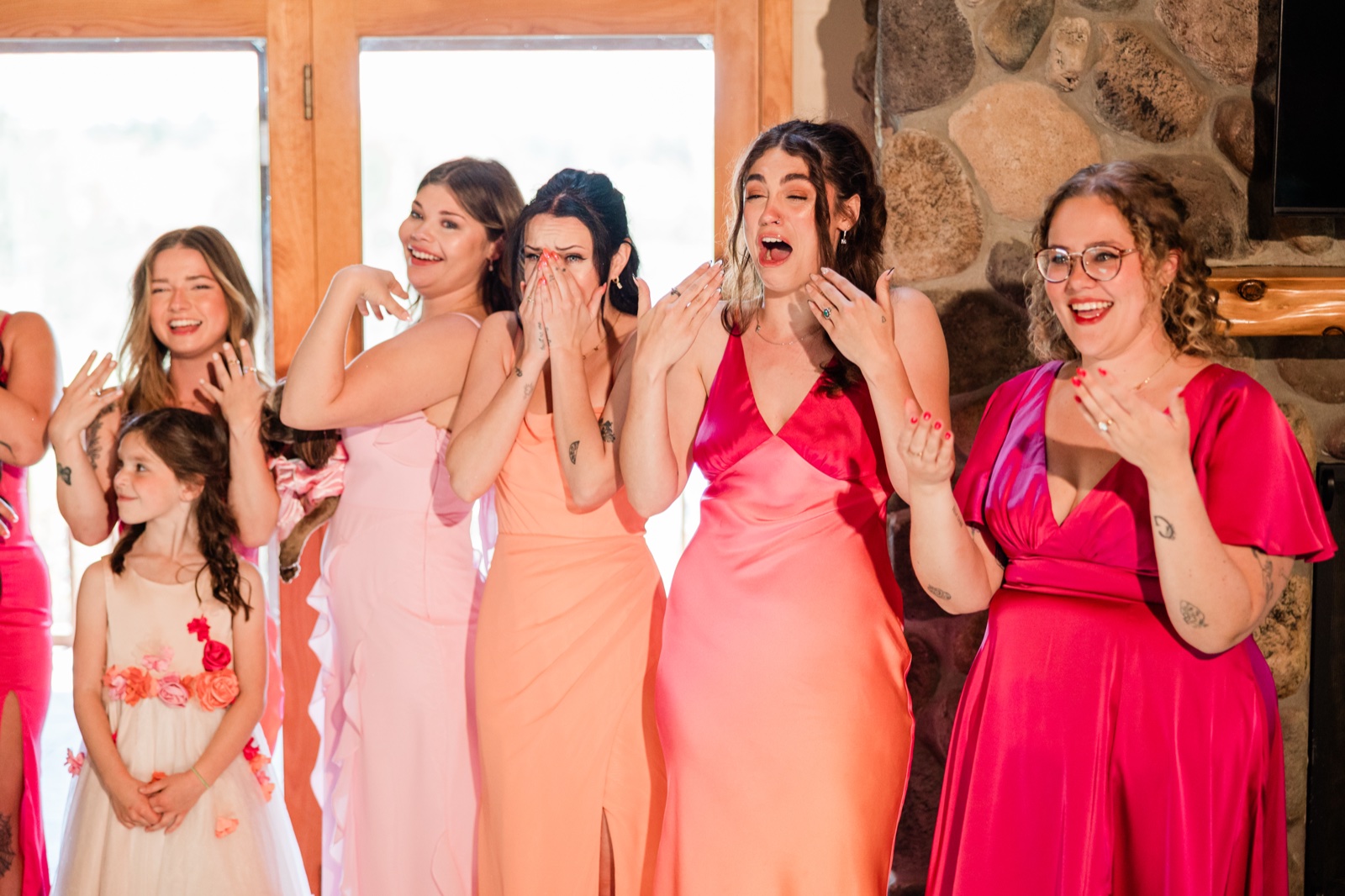 Bridesmaids and flower girl reacting with tears and laughter as they see the bride for the first time