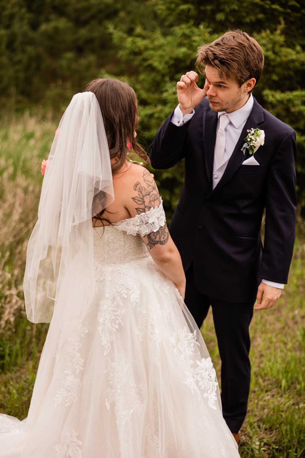 Groom wiping a tear as he sees the bride at their first look in a grassy clearing — Tim Larsen Photography, Brainerd Lakes MN