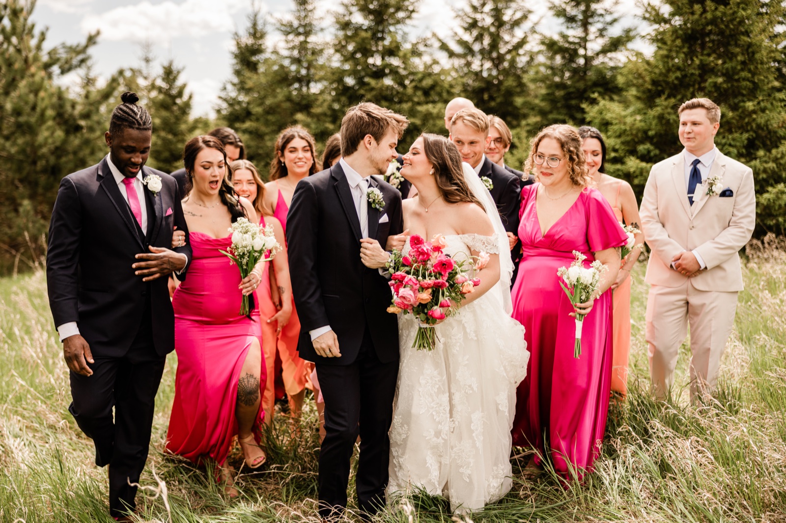 Full bridal party walking through a forest clearing at Pine Peaks Event Center