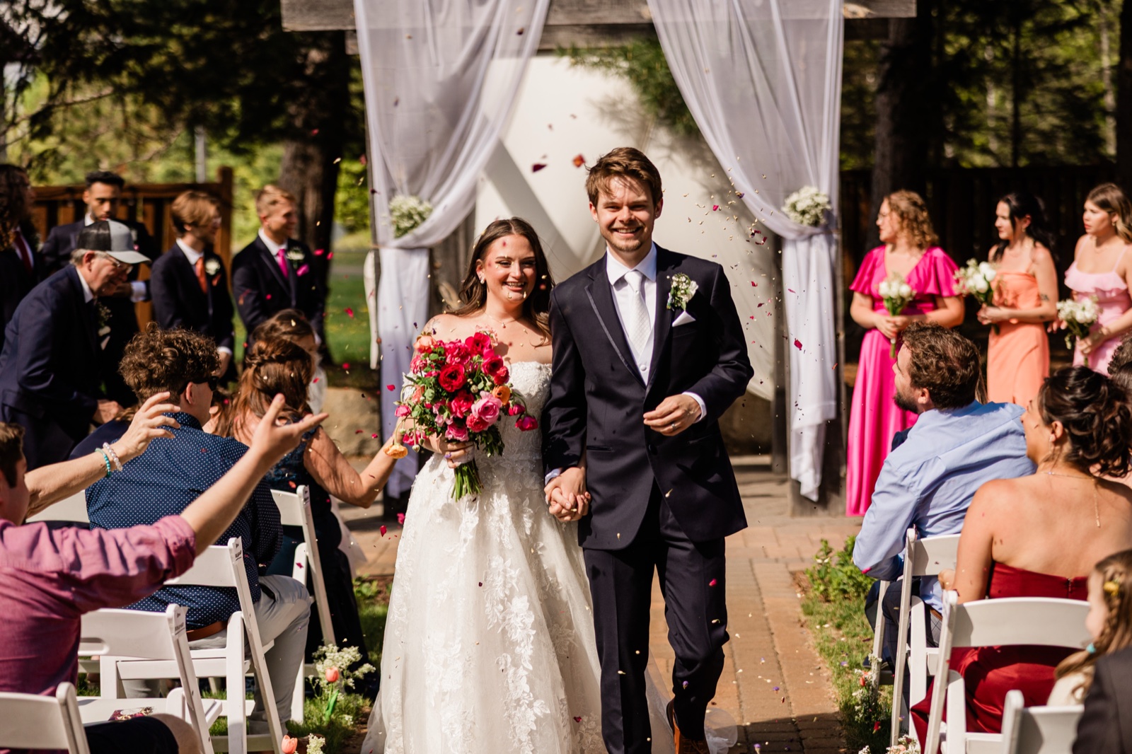 Recessional with petals flying around the bride and groom as they walk hand-in-hand down the aisle