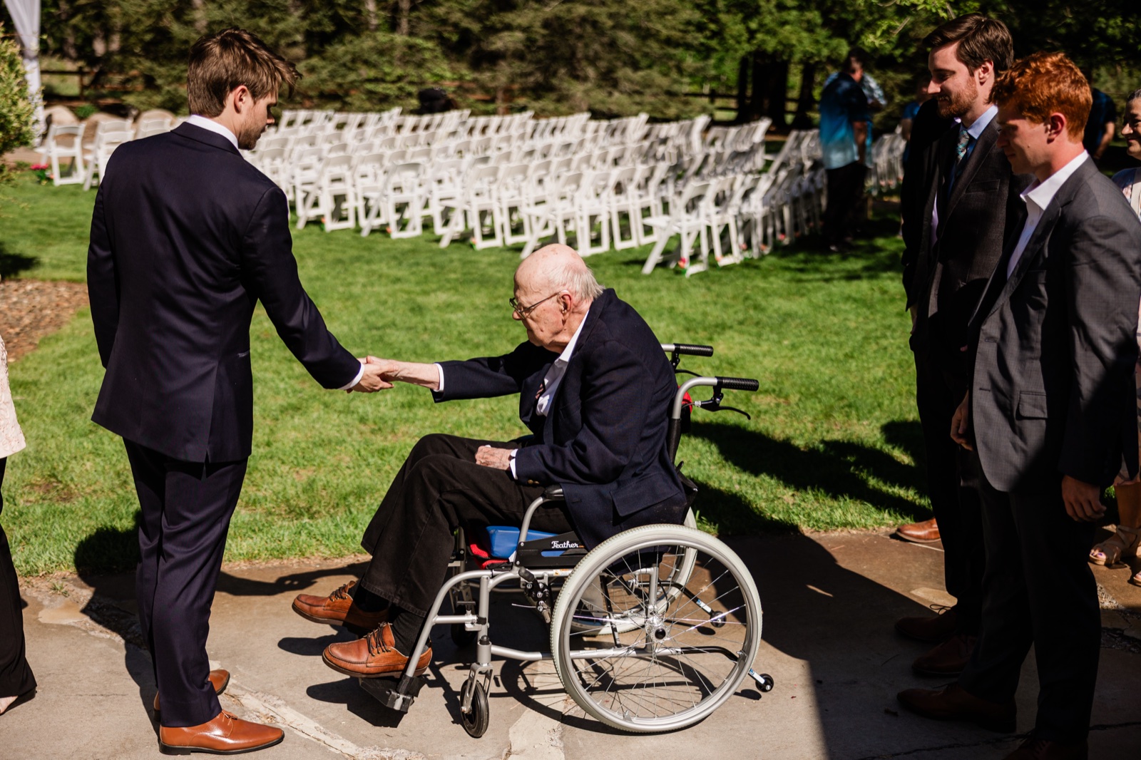 Groom shaking hands with an elder guest in a wheelchair before the ceremony
