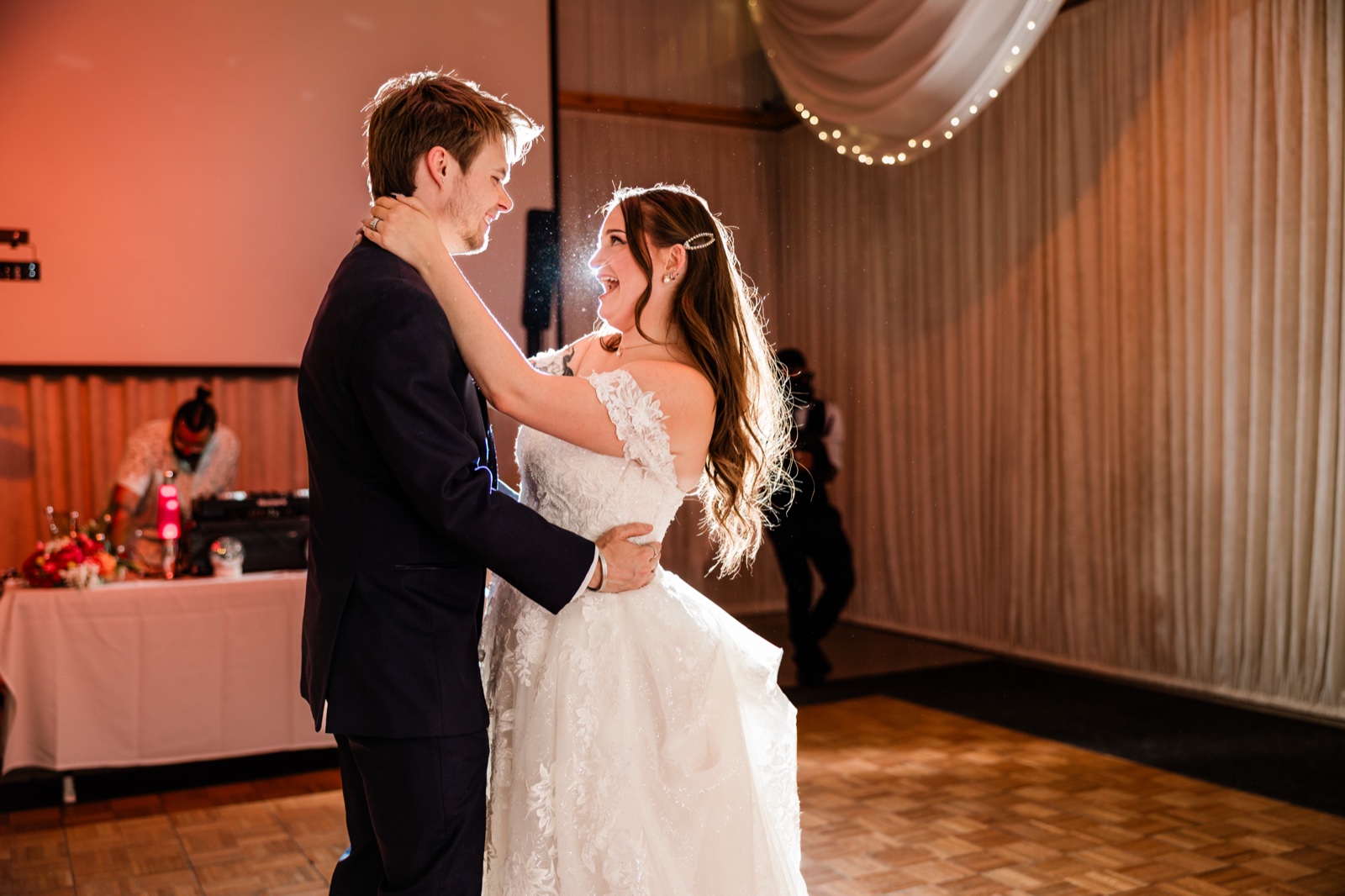 First dance at Pine Peaks Event Center — rim-lit on a cleared wood floor