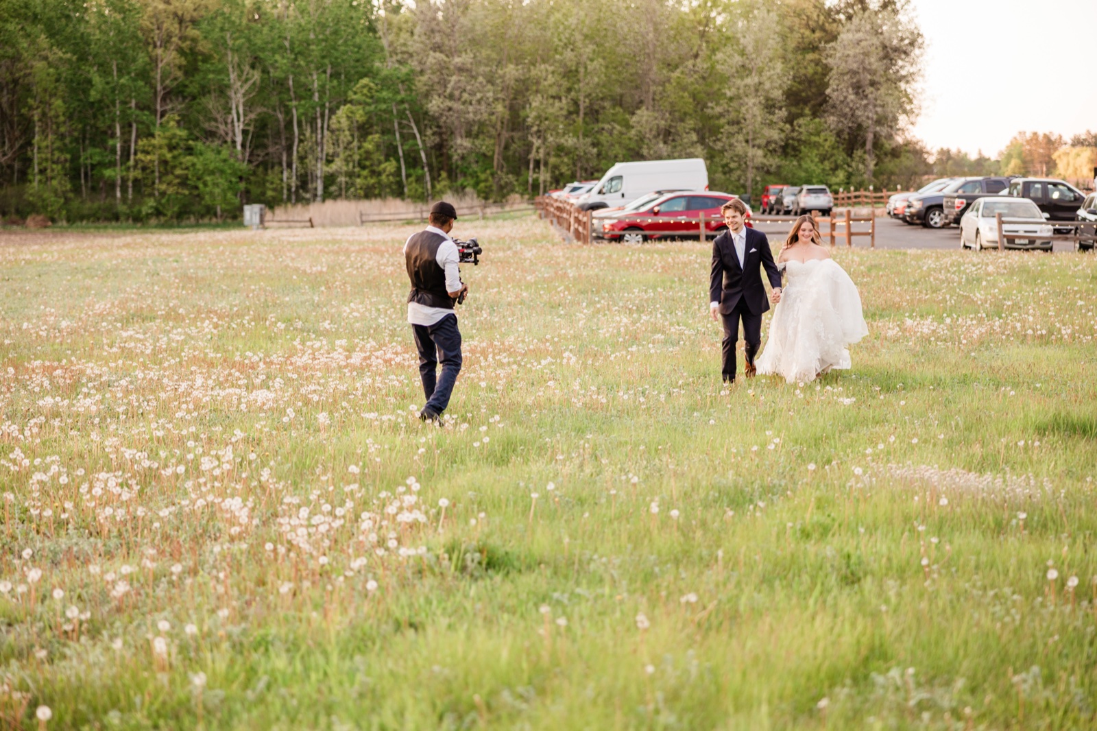 Videographer filming the couple through a dandelion-filled meadow at Pine Peaks
