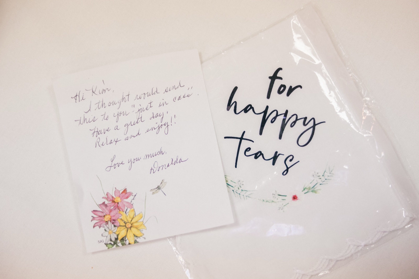 A handwritten note from Kim's mother sits beside a 'for happy tears' embroidered handkerchief on a white surface — Tim Larsen Photography, Brainerd Lakes MN